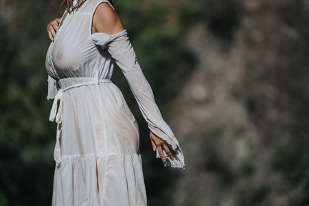 Woman in white sheer dress posing outdoors in sunlightの写真素材