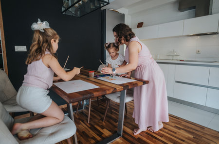 Mother painting with daughters during family bonding time in the kitchenの写真素材