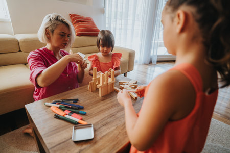 Mother and daughters playing with building blocks at homeの写真素材