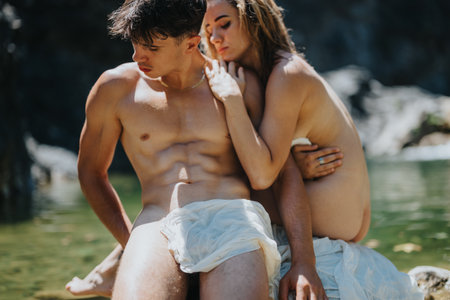 Young couple enjoying a serene moment by a lake, wrapped in white clothの写真素材