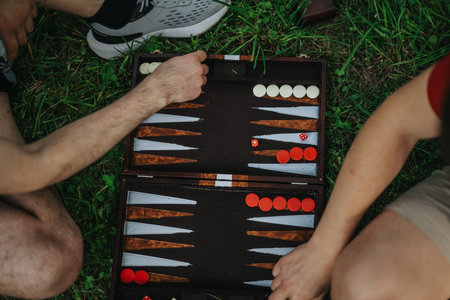 Two friends enjoying an outdoor backgammon game on the grassの写真素材