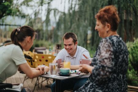 Boy with Down syndrome and friends playing cards outdoorsの写真素材