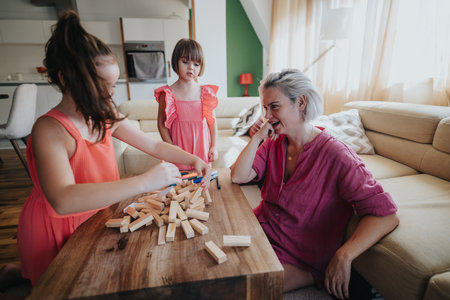 Mother and daughters playing with blocks at home in living roomの写真素材
