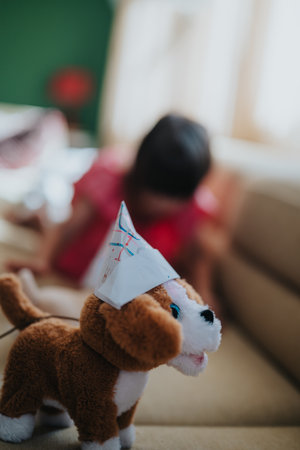 Cute plush dog wearing party hat with child in backgroundの写真素材
