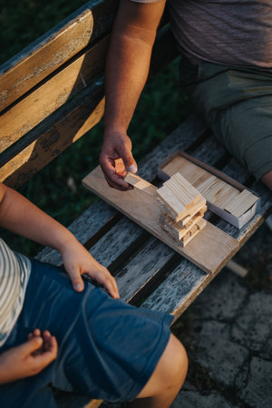 Father and son playing building blocks game on park benchの写真素材