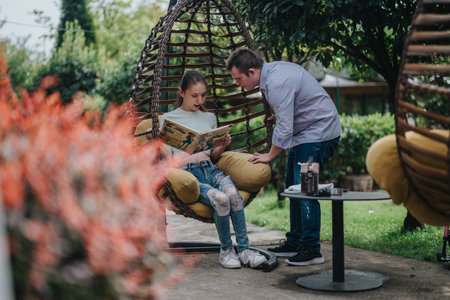 Boy talking to girl in garden swing chairの写真素材