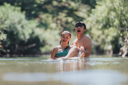 Playful couple enjoying a refreshing swim in a serene riverの写真素材