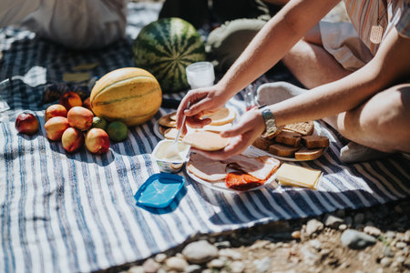 Casual outdoor picnic with fresh fruits and sandwiches on a sunny dayの写真素材