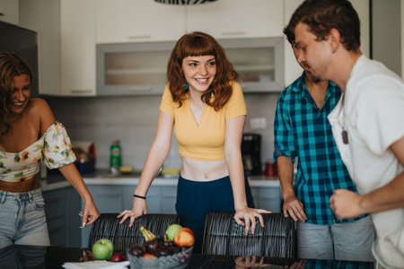Friends laughing together in a modern kitchen settingの写真素材
