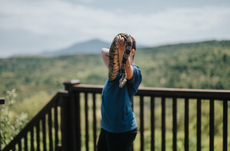 Young girl enjoying time with pet snake on a sunny dayの写真素材
