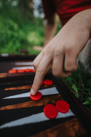 Close-up of hand playing backgammon outdoors on a grassy fieldの写真素材