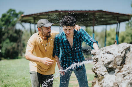 Friends having fun and splashing water at a fountain on a hot summer day in a park
