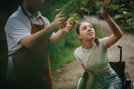 Young woman in wheelchair enjoying nature with assistanceの写真素材