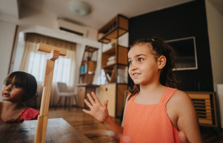Excited children playing with wooden blocks in a cozy living roomの写真素材
