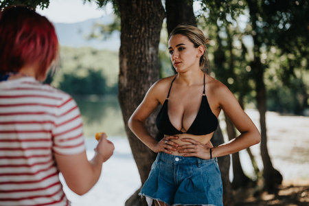 Two friends enjoying summer picnic by the lake in nature settingの写真素材