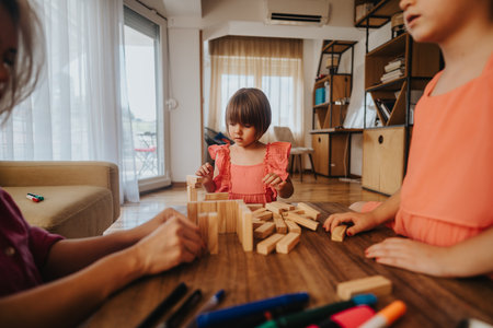 Children playing with wooden blocks in a cozy living roomの写真素材