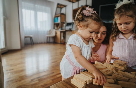 Mom spending quality time with her daughters playing with wooden blocks at homeの写真素材