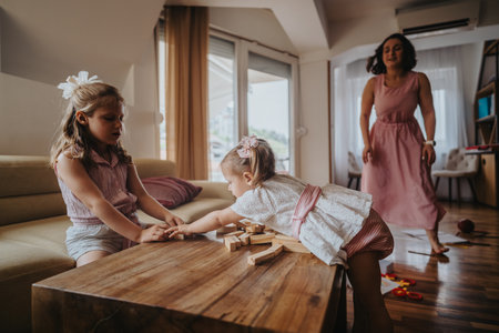 Mother with daughters playing with wooden blocks at home, strengthening family bondsの写真素材