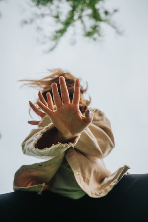 Person reaching out with open hand from below perspective outdoorsの写真素材