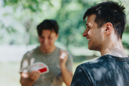 Friends playing cards and enjoying a sunny day outdoorsの写真素材