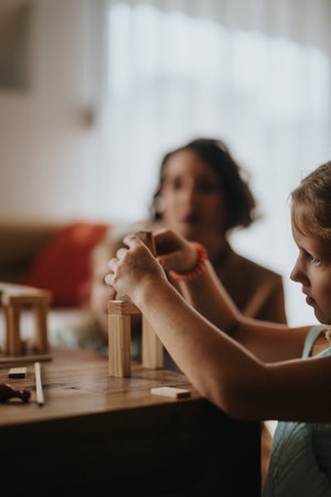 Mom and daughters playing with wooden blocks at homeの写真素材