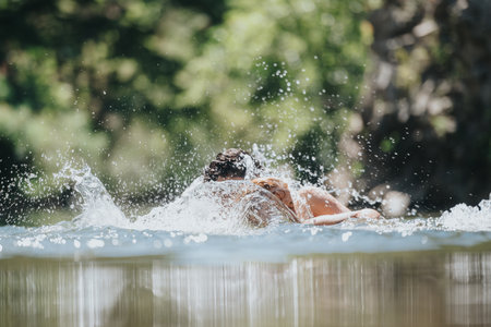 Couple swimming in clear lake surrounded by lush green treesの写真素材