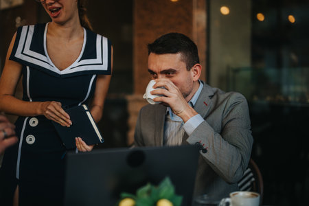 Business meeting at a cafe with professionals engaging in discussion over coffee and a laptop, focusing on teamwork and collaboration in a casual settingの写真素材