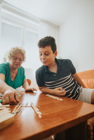 Grandmother and grandson enjoying a game of pick up sticks at homeの写真素材
