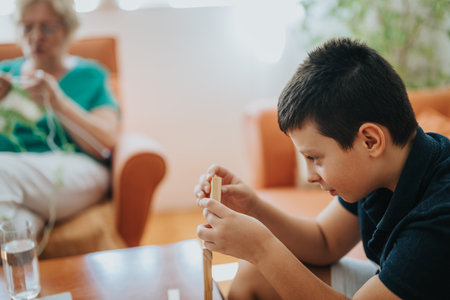 Grandmother knitting while nephew plays with building blocks at homeの写真素材
