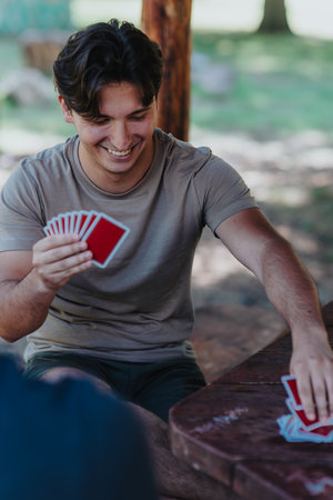 Young man enjoying a card game with friends outdoorsの写真素材