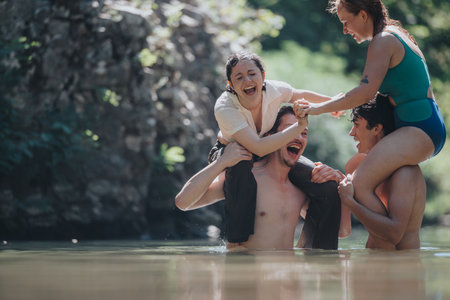 Young friends enjoying playful moments in a sunny river settingの写真素材