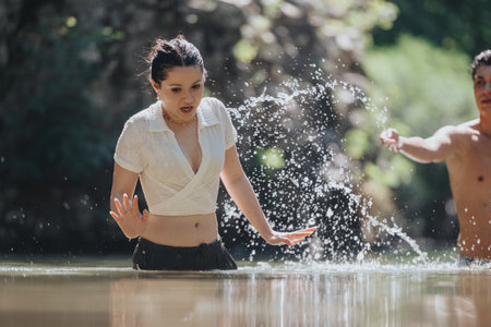 Playful moment of friends splashing water in a natural settingの写真素材