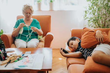 Young boy scrolling phone as grandmother knits a vest for him