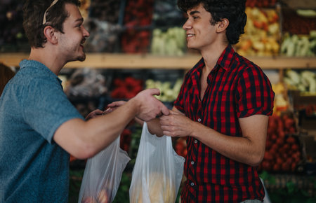 Friends joyfully buying fresh fruits and vegetables at a marketの写真素材