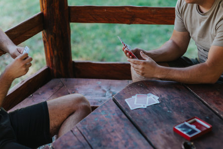 Two friends enjoying a relaxing game of cards outdoorsの写真素材