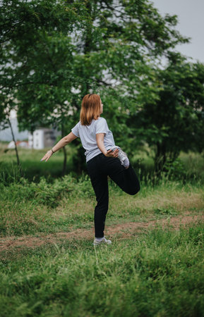 Woman practicing yoga outdoors in a lush green park setting