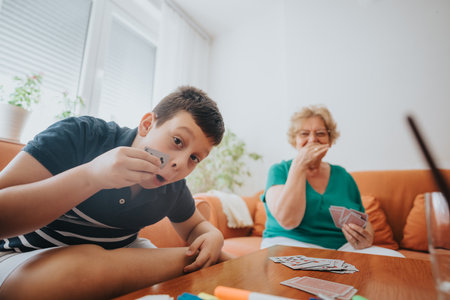 Grandmother and grandson having fun playing a card game at home