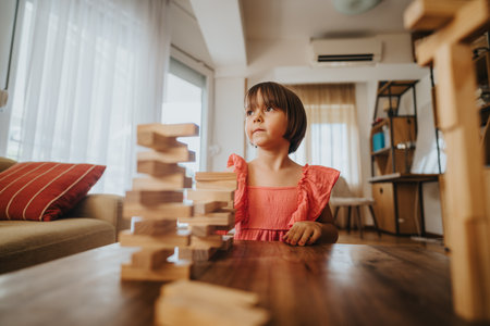 Young girl playing with wooden blocks in a cozy living roomの写真素材