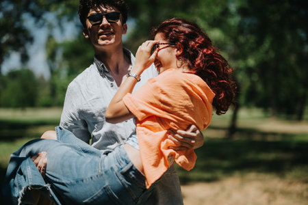 Young couple having fun outdoors with the man carrying the woman on a sunny dayの写真素材