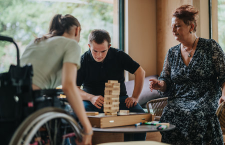 Boy with Down syndrome, girl in wheelchair and elderly woman playing togetherの写真素材