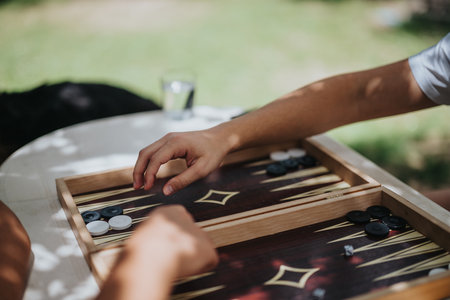 Friends enjoying a game of backgammon outdoors on a sunny dayの写真素材