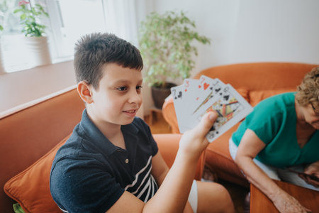 Young boy enjoying a card game with family indoorsの写真素材