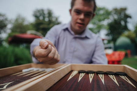 Boy with Down syndrome enjoying backgammon game outdoorsの写真素材