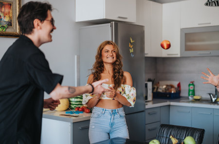 Friends enjoying playful moments in a modern kitchen settingの写真素材