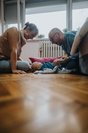 Happy family bonding time with baby on living room floorの写真素材