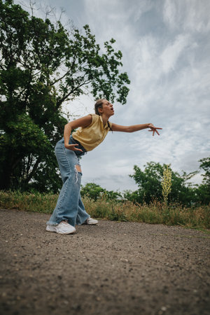 Young woman in casual outfit striking a playful pose outdoorsの写真素材