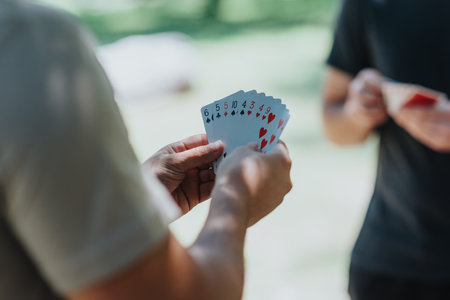 Close-up of hands holding playing cards outdoorsの写真素材