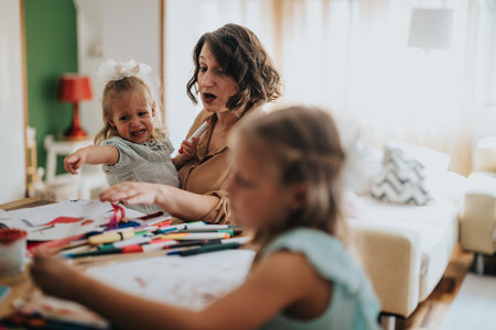 Mom enjoying creative art time with young daughters at homeの写真素材