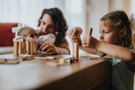 Mother and daughters playing with wooden blocks at homeの写真素材