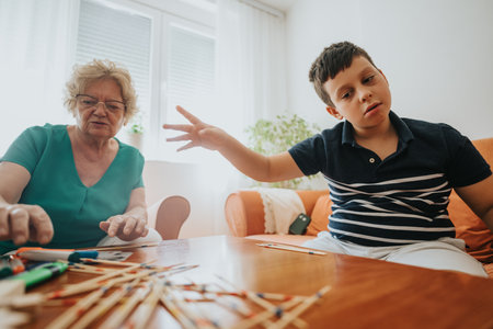 Young boy playing pick-up sticks with grandmother in cozy living room